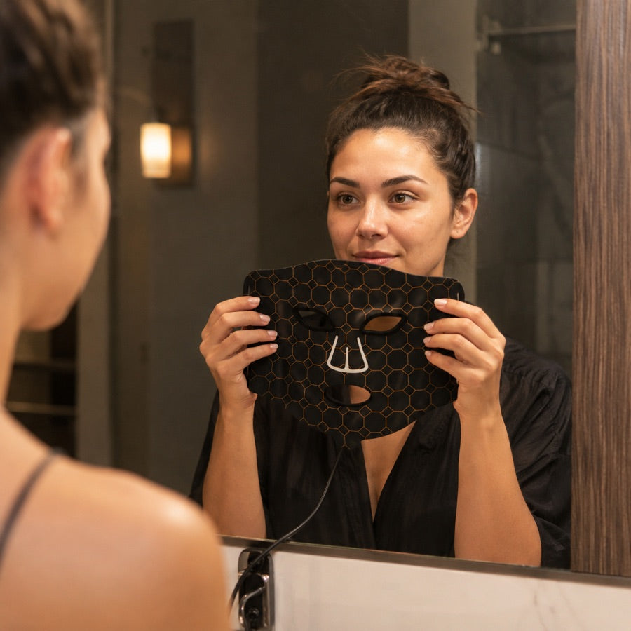 Woman beginning her LED FLEX Mask ritual at the bathroom mirror