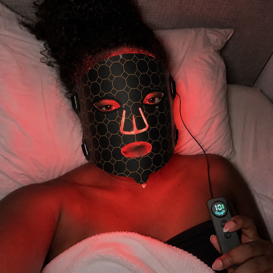 Woman winding down in bed with the red LED FLEX Mask setting