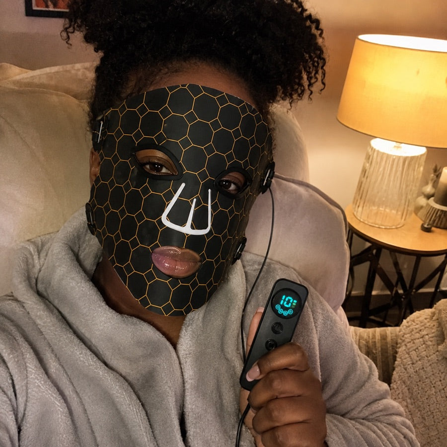 Woman relaxing in a robe with the LED FLEX Mask and controller