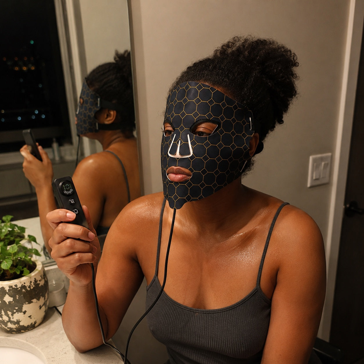 Woman holding the LED FLEX Mask controller during her evening mirror ritual